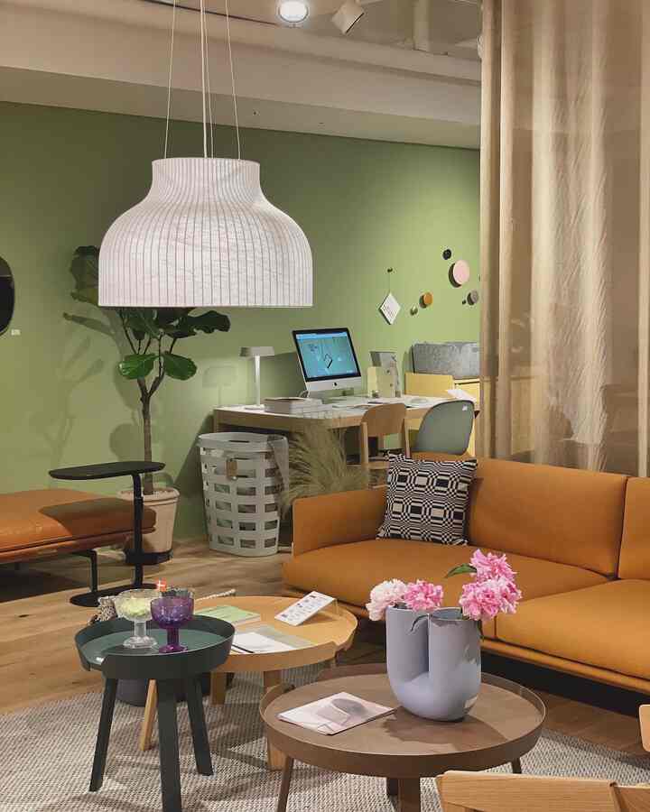 Natural tone living room featuring an orange sofa, wooden coffee tables, and a light green wall creating a warm, clean atmosphere