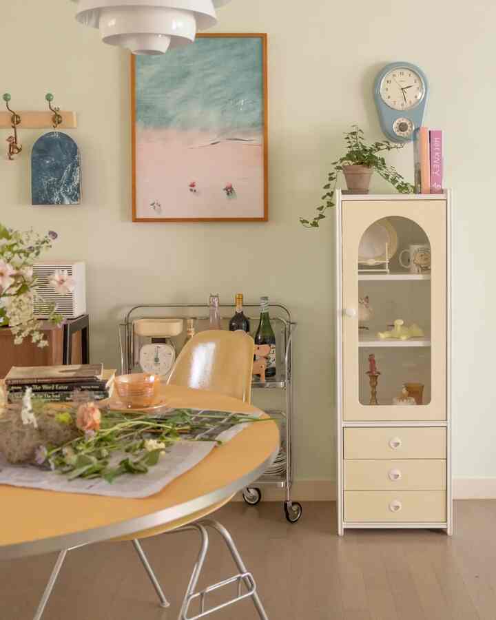 Beige and light green toned dining room featuring a round dining table and vintage clock with a natural atmosphere
