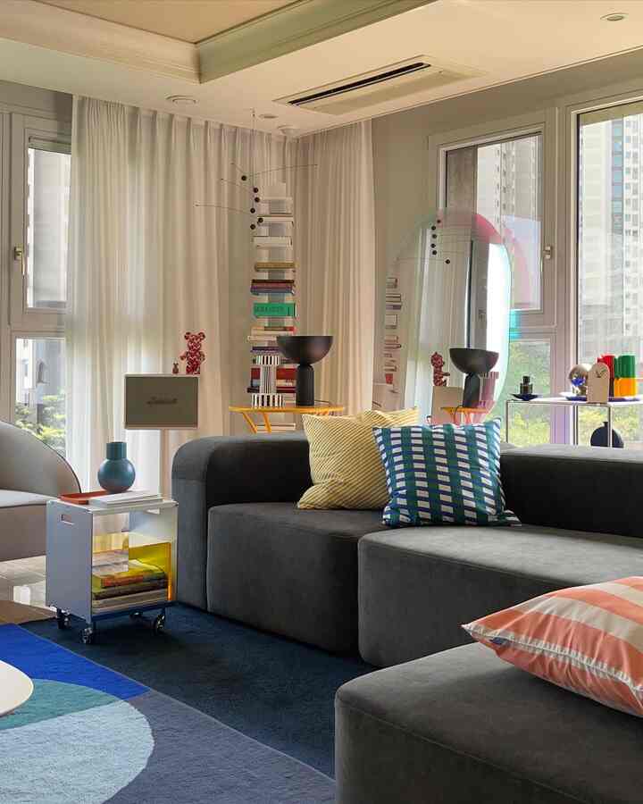 Mid-Century Modern living room with white curtains and blue, gray-toned cushions arranged on a sectional sofa