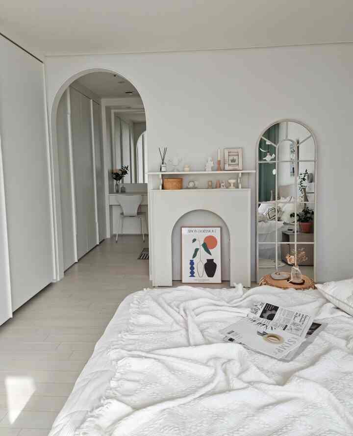 明るく清潔感のある白を基調とした寝室、アーチ形の間仕切りとクローゼット、化粧台が調和したモダンなインテリア