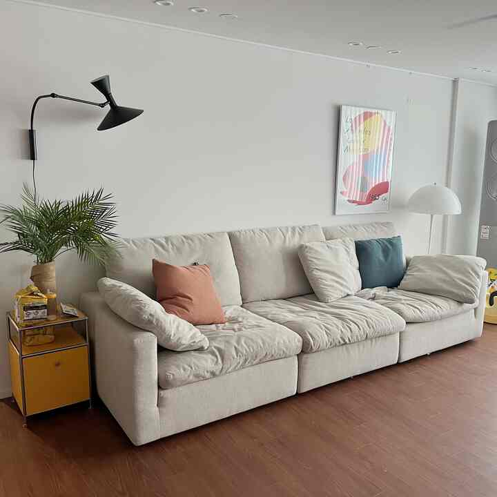 Beige-toned living room featuring a large sofa with cushions and a yellow side table in a simple and natural setting