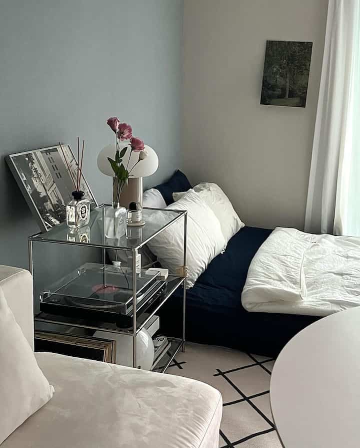 ホワイトとネイビーカラーが調和したワンルームの寝室、モダンな家具とシンプルなインテリアが配置された落ち着いた空間