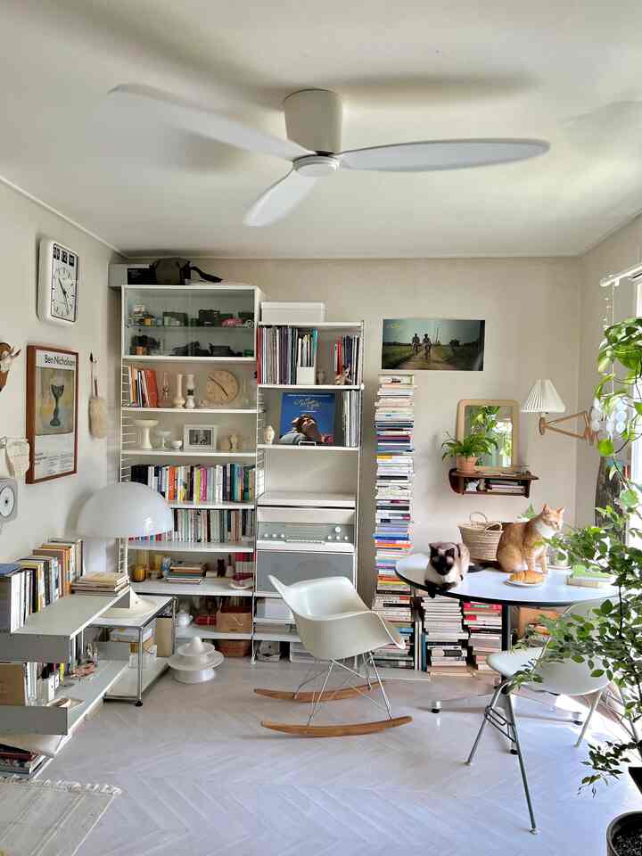 ホワイトとナチュラルカラーのダイニングルーム、丸テーブルの上に2匹の猫とイームズアームチェアが配置された落ち着いた雰囲気のインテリア