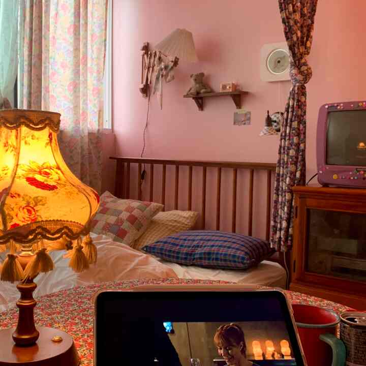 Cozy vintage bedroom featuring pink walls, floral-patterned curtains, and a wooden bed frame