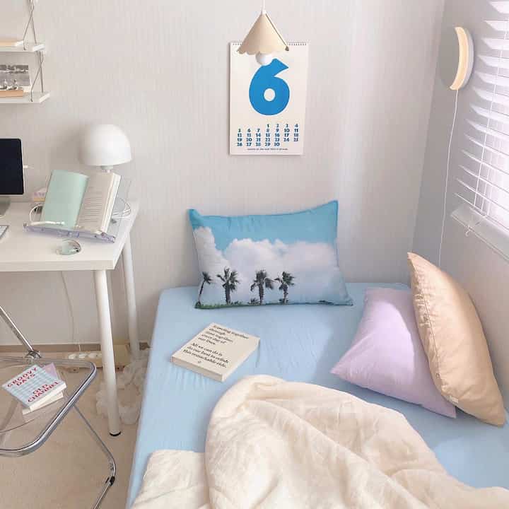 White and blue toned bedroom featuring a compact desk and bed with a simple, modern atmosphere