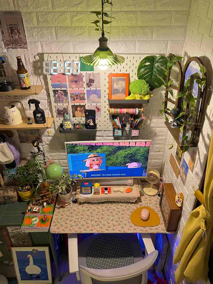 ホワイトとグリーンのトーンが特徴の小さなホームオフィス、デスクとペンダントライト、植物が配置された雰囲気のあるインテリア