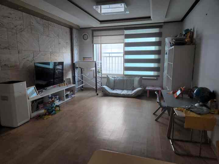 白と茶色のトーンのコンパクトなリビング、座敷ソファと子供用机、テレビ台が配置された実用的で落ち着いた雰囲気のインテリア