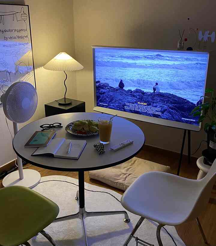 白と黒のトーンのダイニングルーム、丸テーブルと椅子、テレビが配置された居心地の良いホームカフェとホームオフィスの空間