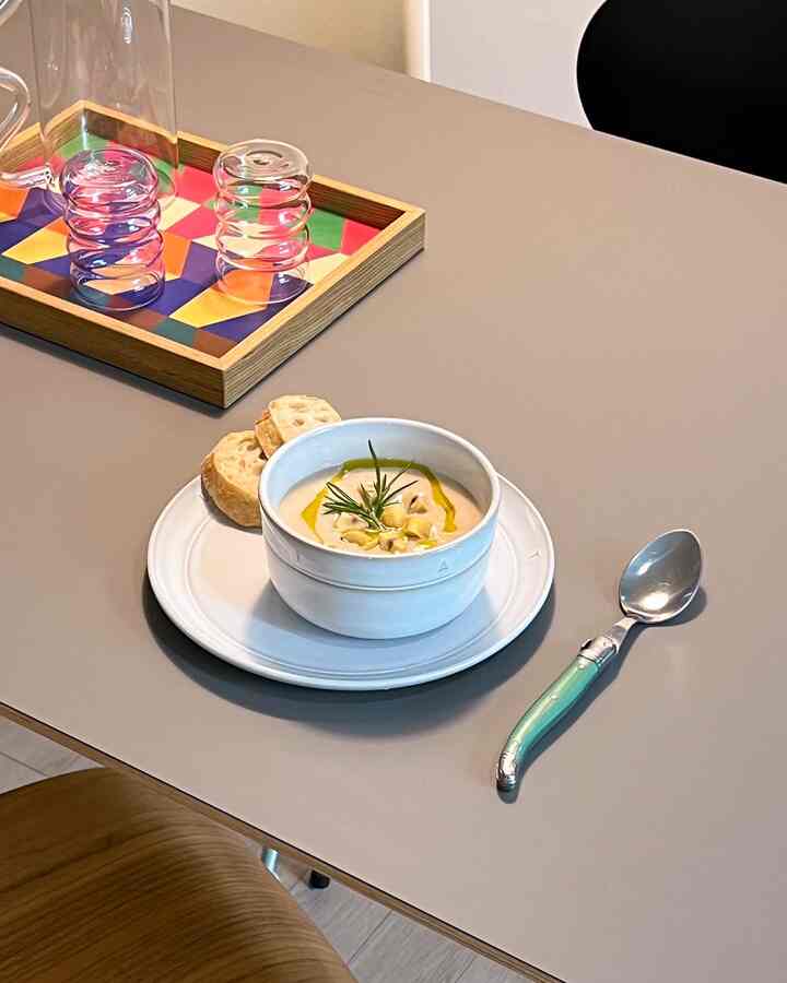 ナチュラルカラーのダイニングテーブルに白い食器とカトラリーが配置されたモダンなキッチンまたはダイニングの雰囲気あるインテリア