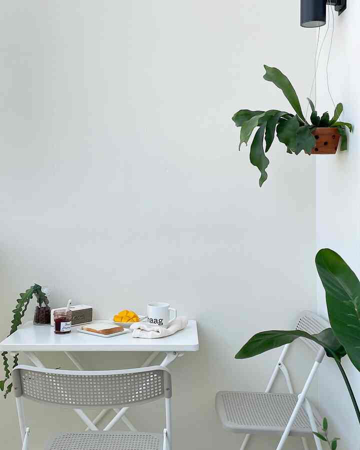 White-toned small home cafe space with folding dining table and chairs creating a simple and relaxed atmosphere