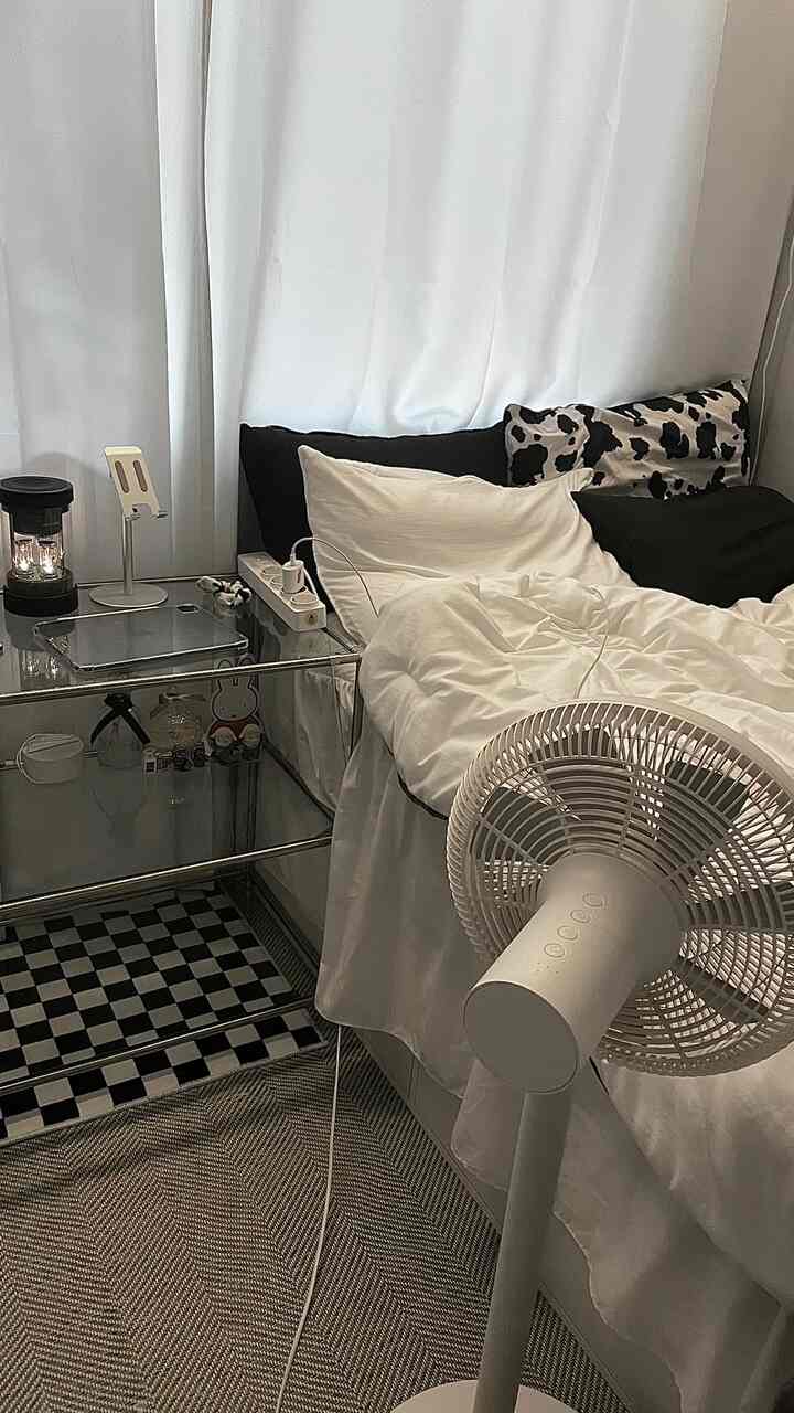 A modern single bedroom in white and black monotone, featuring a bed, curtains, and a rug in a compact space