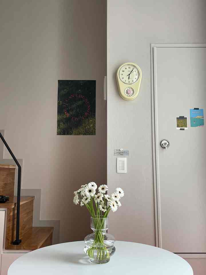 Natural tone entrance and stair space featuring a white round table with a vase of white flowers in a clean interior