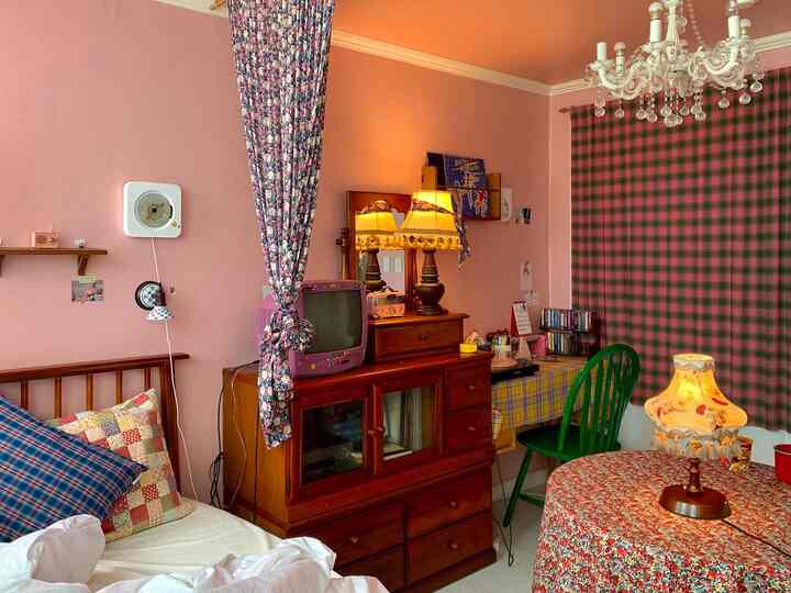 Pink walls and wood furniture complement floral fabric curtains in a vintage retro bedroom space