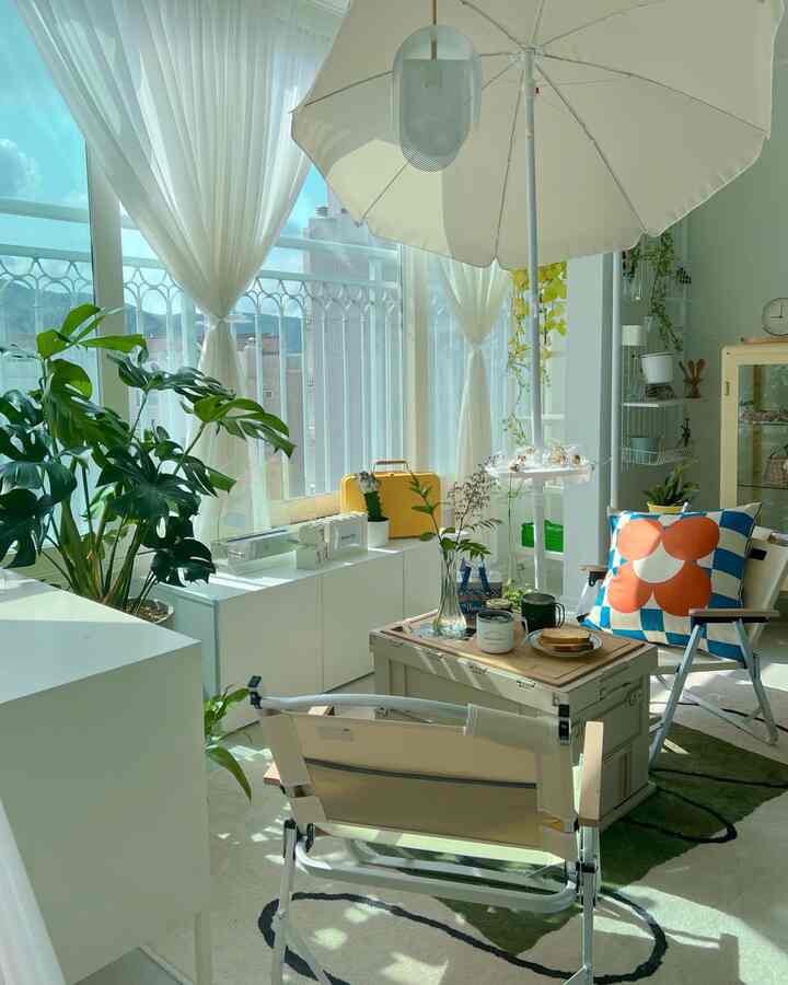 Bright beige and white veranda space featuring camping chairs, a parasol, and home cafe style for cozy ambiance