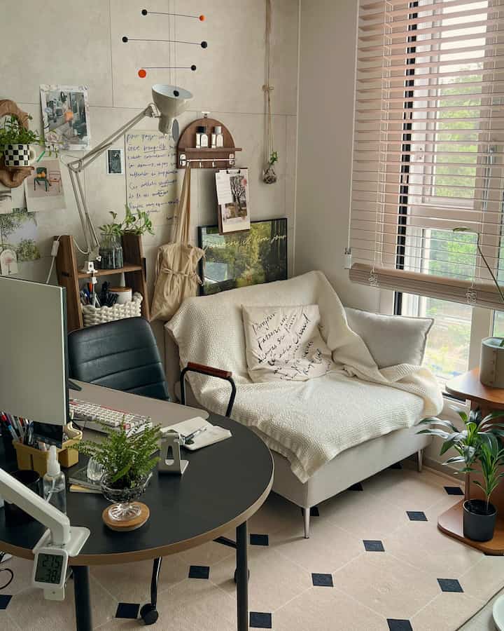 Natural-toned living room and home office featuring an ivory sofa, round black table, and lush indoor plants creating a cozy atmosphere
