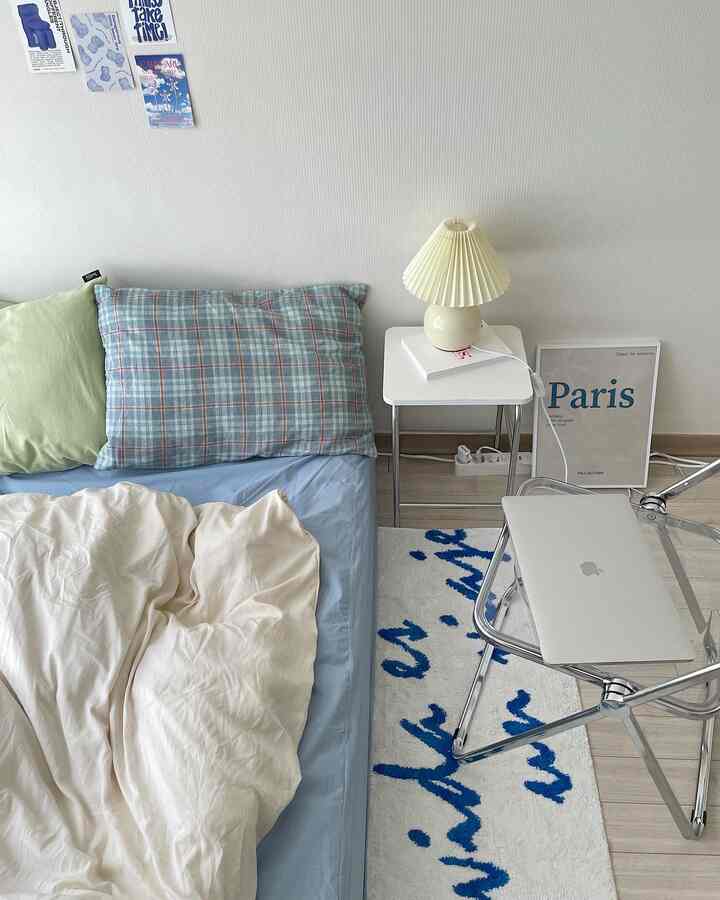 White and blue toned bedroom featuring a transparent folding chair and simple lamp creating a cozy atmosphere