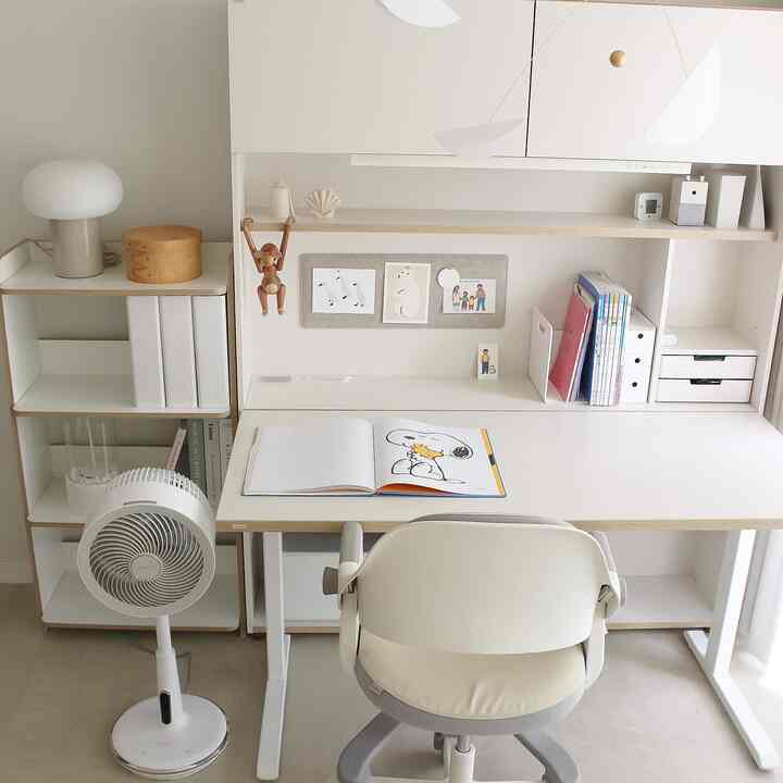 A white and beige toned kids' room featuring a desk and chair centrally placed, with neat and simple organization throughout