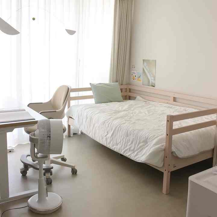 Natural tone kids' room featuring a wooden daybed with white bedspread, clean and bright atmosphere