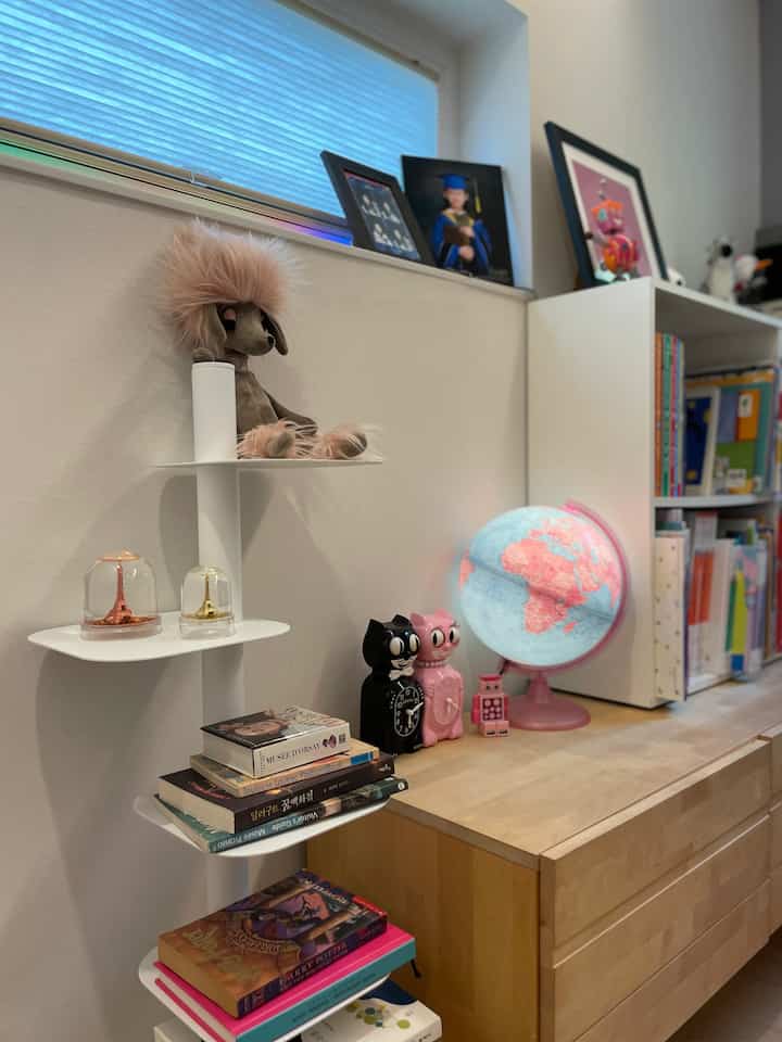 Kids' room with white walls and wood tone furniture, featuring bookshelves, toys, and child-friendly decor for cozy ambiance
