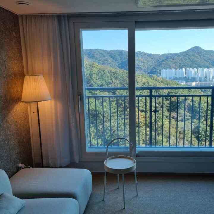 白とナチュラルトーンのリビング、ソファとサイドテーブル、フロアランプが配置されたシンプルな空間