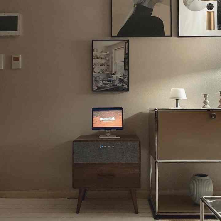Beige-toned cozy living room wall with nightstand featuring a monitor and framed art in a simple interior