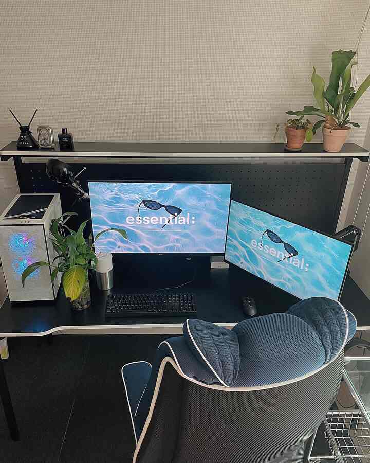 Black and white toned desk space featuring dual monitors and a gaming chair in a modern, compact home office
