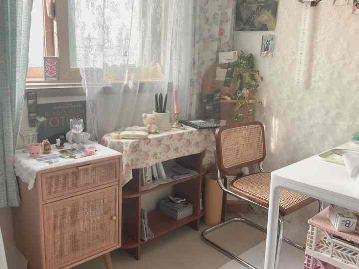 白いレースカーテンとナチュラルなベージュのラタンチェアがある小さな居心地の良い部屋