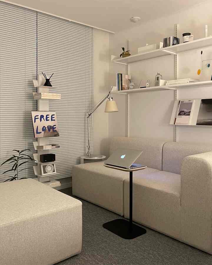 Beige and ivory toned study space featuring sofa, side table, and bookshelves with a cozy and tidy interior
