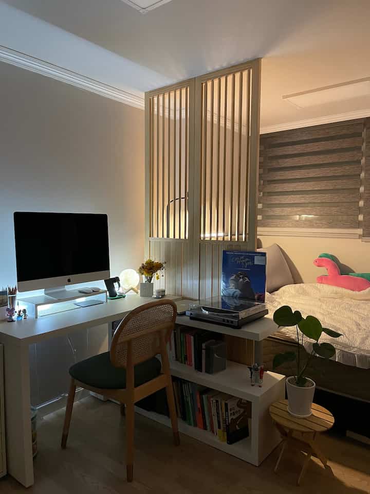 Cozy small room with white and wood tones, featuring a wooden partition dividing workspace and bedroom