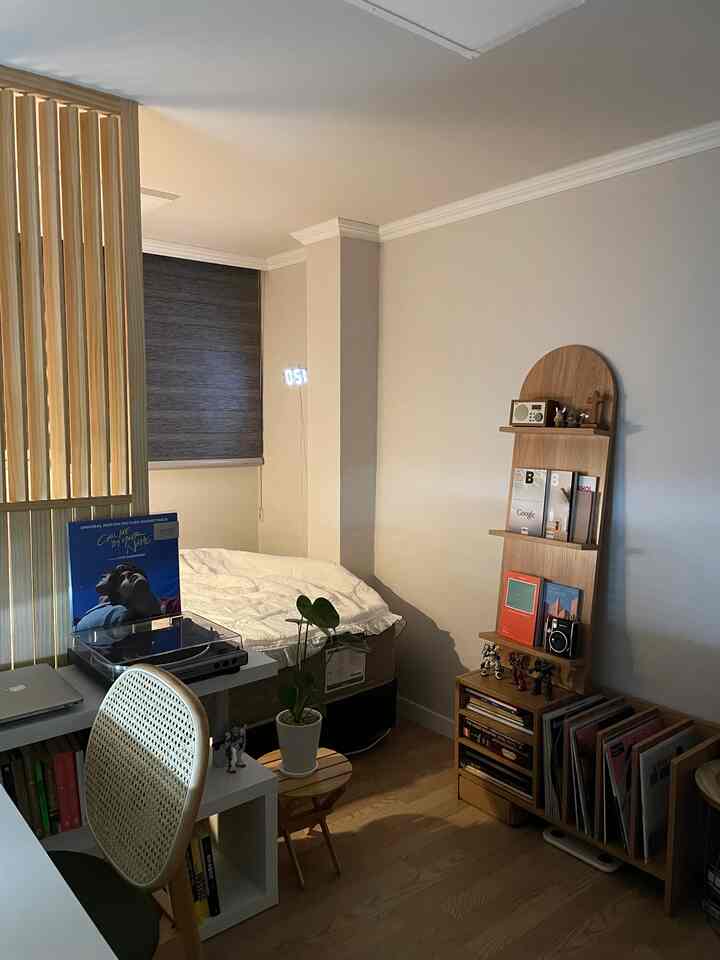 Compact single household bedroom and study with white walls and wooden furniture