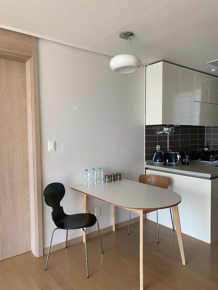 白とナチュラルカラーのキッチン、木製ダイニングテーブルと椅子が配置された洗練されたモダンな空間