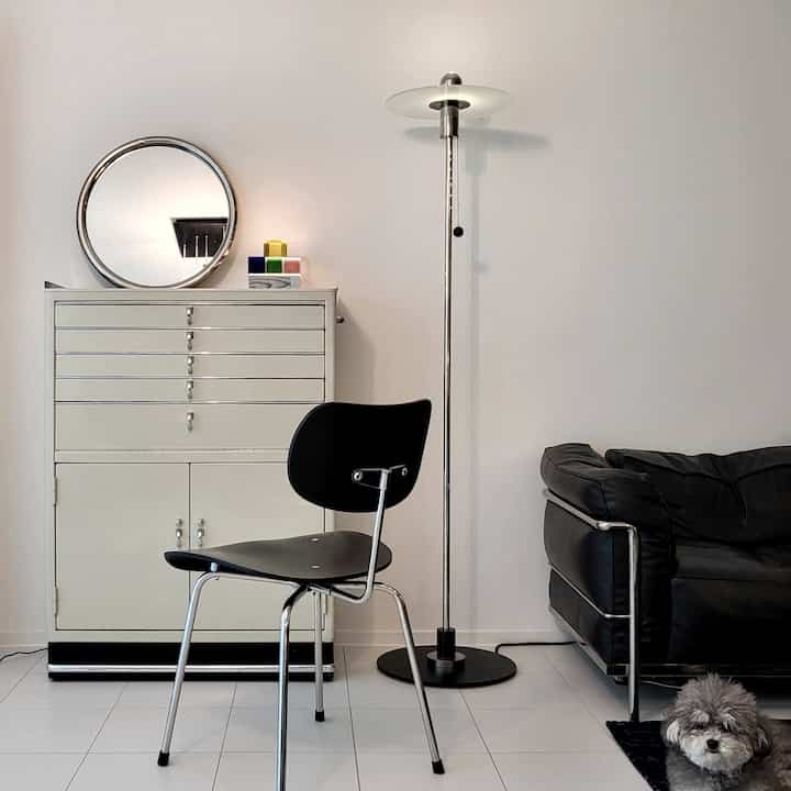 白と黒のトーンのリビング、ヴィンテージの鉄製キャビネットと黒いソファが配置された落ち着いた雰囲気のインテリア