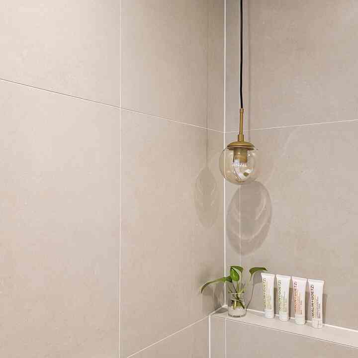 Beige bathroom corner featuring a pendant light and a small green plant in a clean minimalist setting