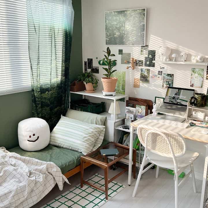 Natural green and white toned bedroom with compact desk and plants, creating a cozy and fresh atmosphere