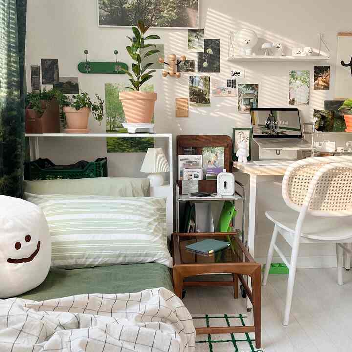 A simple modern small bedroom in white and green tones featuring a desk and plants, creating a cozy atmosphere