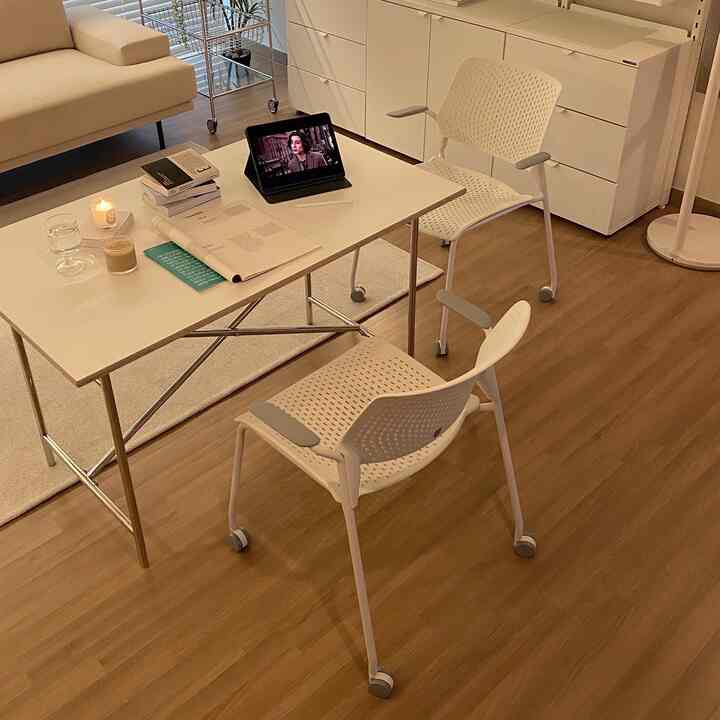 White and brown toned living room and home office featuring white desk and chairs, iPad, and candle creating a cozy workspace