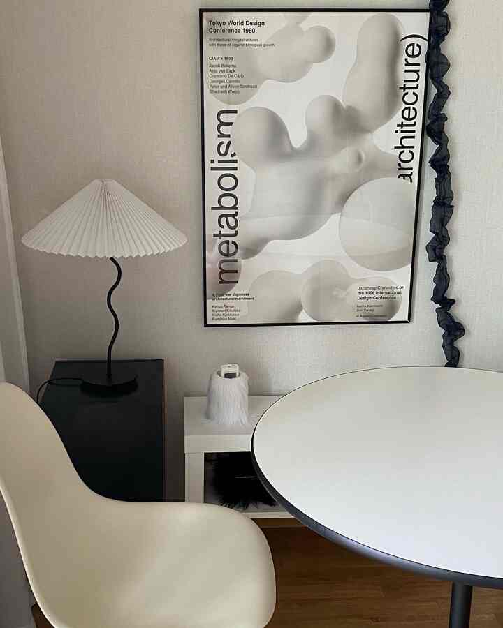 白と黒の色調のリビング、ミッドセンチュリーモダン様式のダイニングテーブルと椅子、抽象的なポスターが配置された印象的な空間