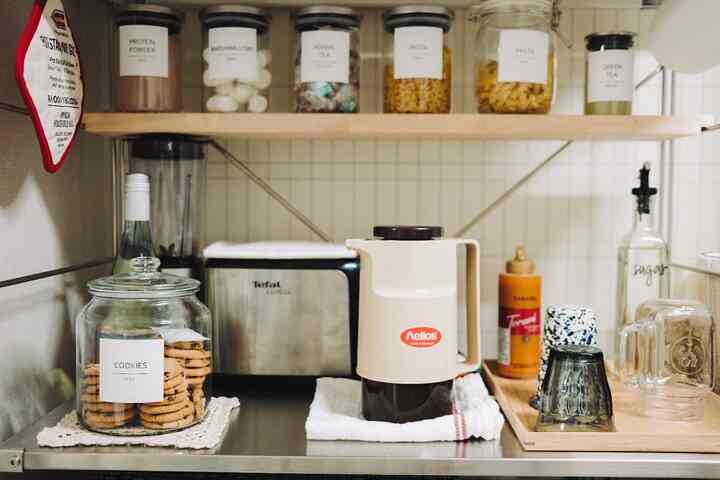 Natural wood tone and beige kitchen space featuring organized cookie jar, vacuum glass thermos, and kitchen essentials creating a clean atmosphere