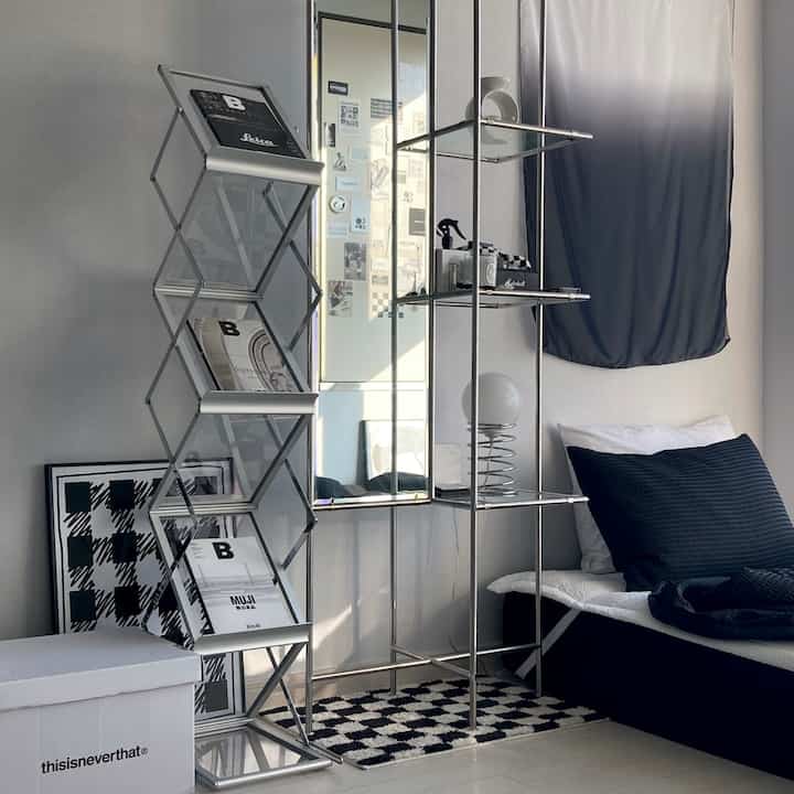 Black and silver toned living room featuring a metal magazine rack and shelving with simple, modern decor