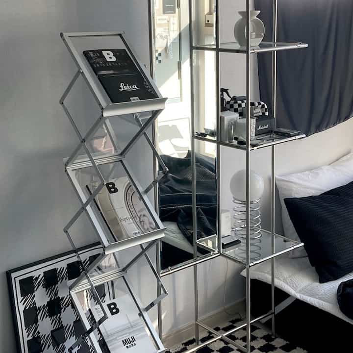 Modern living room in silver tone featuring a magazine rack and metal shelves neatly arranged with interior accessories