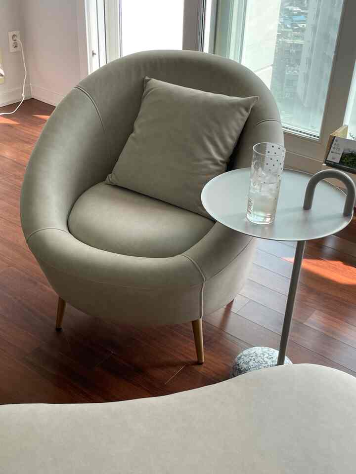 Natural-toned studio living room featuring a beige armchair and side table creating a cozy space