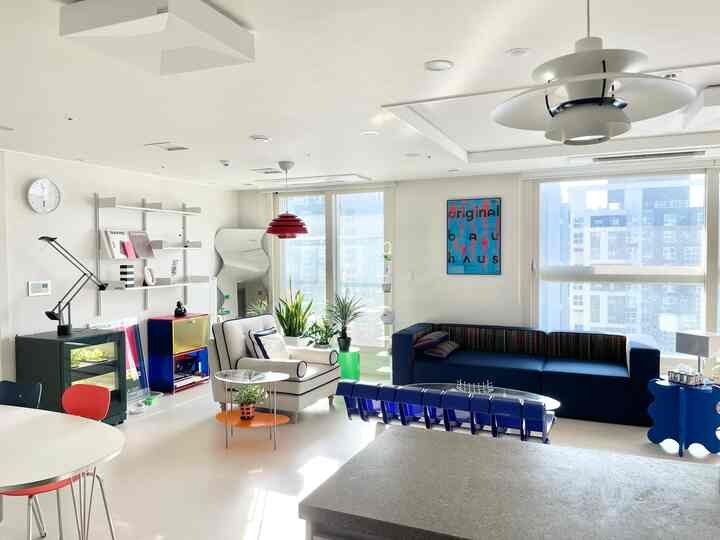 Bright modern living room with white walls and floors featuring a blue sofa and armchair