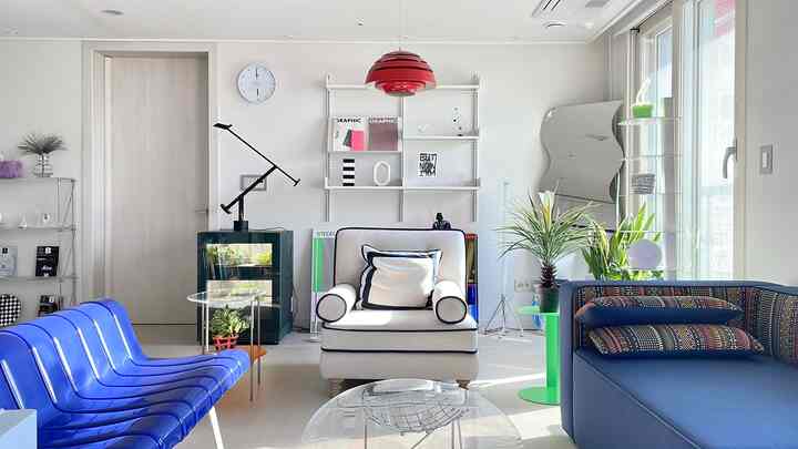 白い壁と青いソファが調和するリビング、モダンな家具と植物が配置された明るく落ち着いた空間