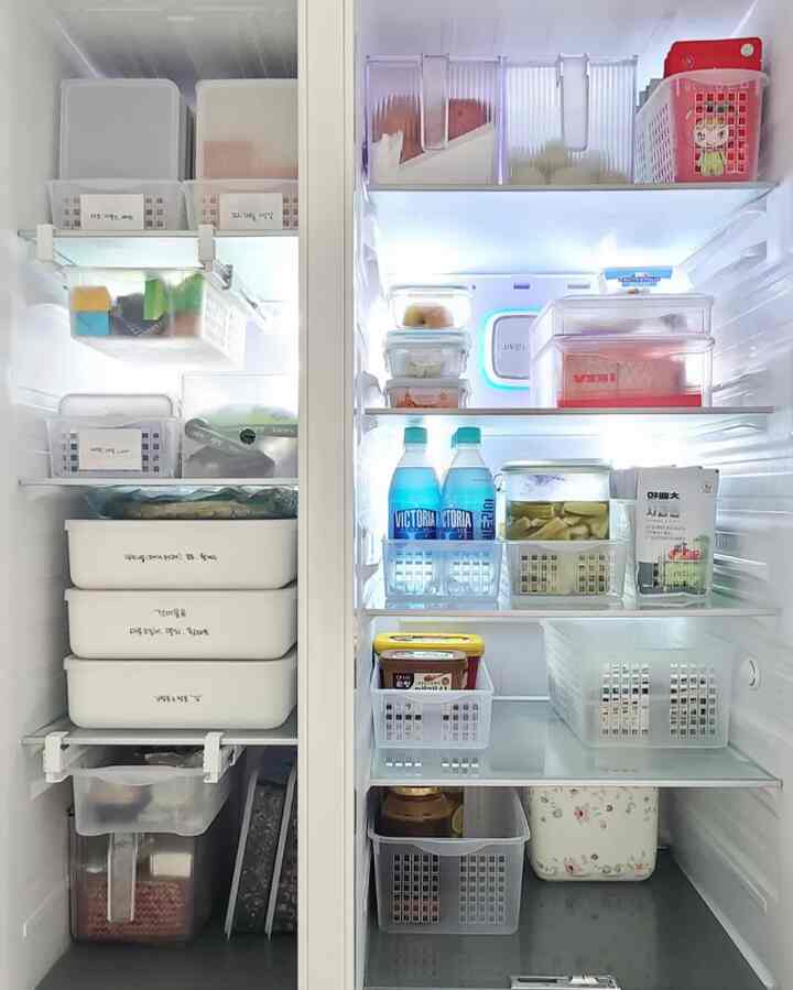 Bright white fridge interior neatly organized with transparent plastic containers and trays