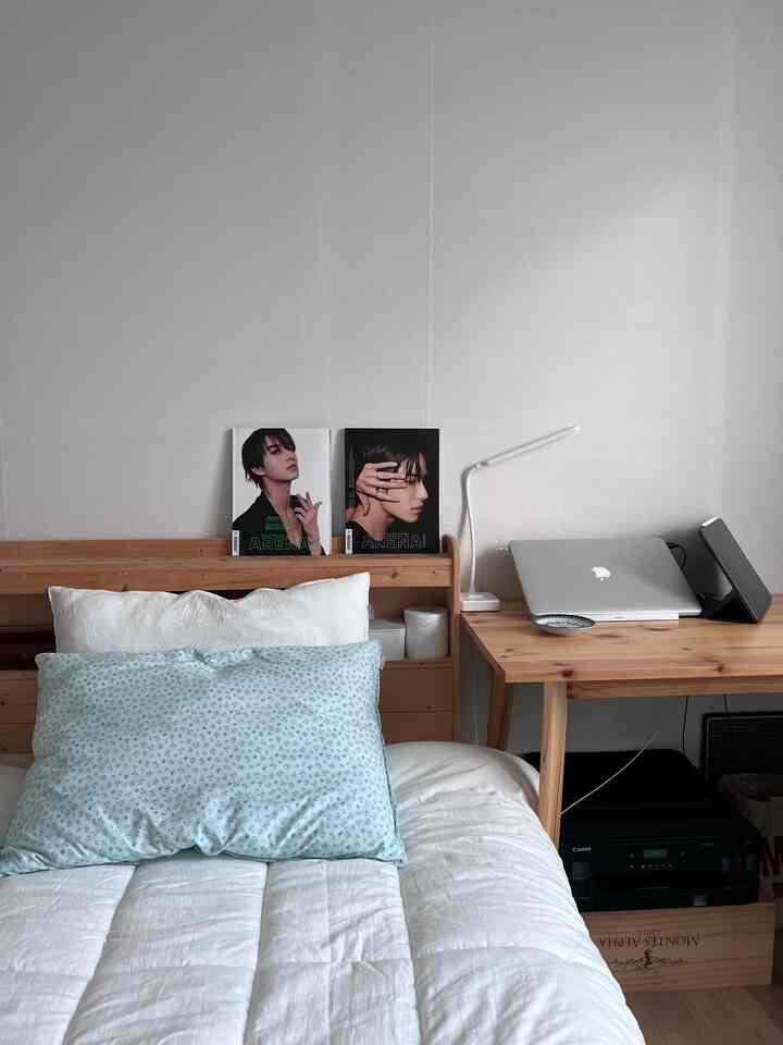 ホワイトと木目調の寝室、ベッドと枕、横にノートパソコンと照明のあるホームオフィス空間が配置された落ち着いた雰囲気のあるインテリア