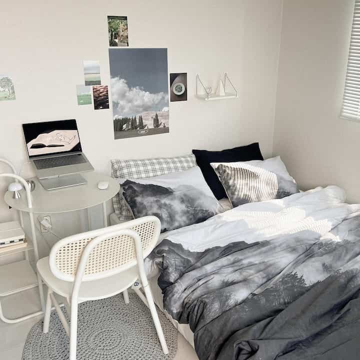 Modern bedroom in white and gray tones featuring a round table with a laptop, creating a cozy atmosphere