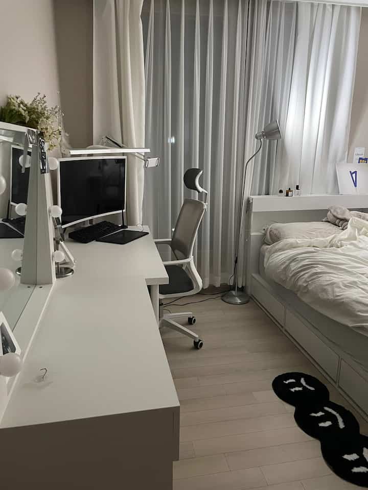 White and light brown toned bedroom with desk and office chair arranged for a neat home office and living space