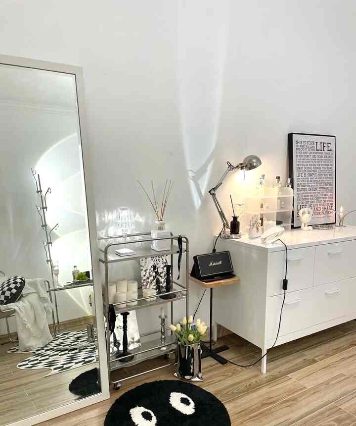 ホワイトと木目調が調和したリビング、全身鏡と収納キャビネット、マーシャルスピーカー、照明が配置されたミニマルな空間