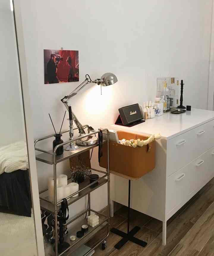 Minimalist small room with white walls and drawer cabinet, featuring metal storage cart and floor lamp with neat décor