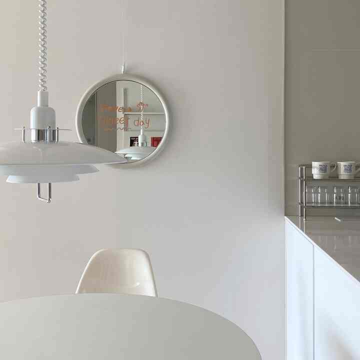 白を基調としたキッチンとダイニングスペース、丸いダイニングテーブル、ペンダントライト、壁面の丸い鏡が配置された清潔感のあるモダンなインテリア
